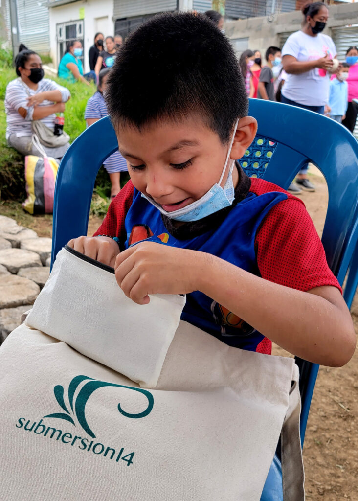 A young boy in Peronia City, Guatemala, looks through his submersion14 goody bag with excitement.